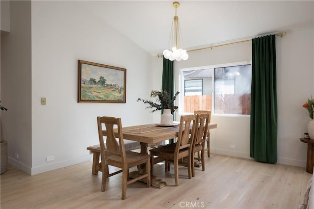 dining room with baseboards, a notable chandelier, light wood-style floors, and lofted ceiling