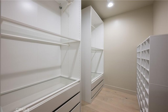walk in closet with light wood finished floors