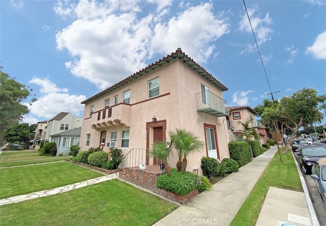 2200 Chestnut, Long Beach, CA 90806 - view of side of home featuring stucco siding, a tiled roof, a lawn, and a balcony
