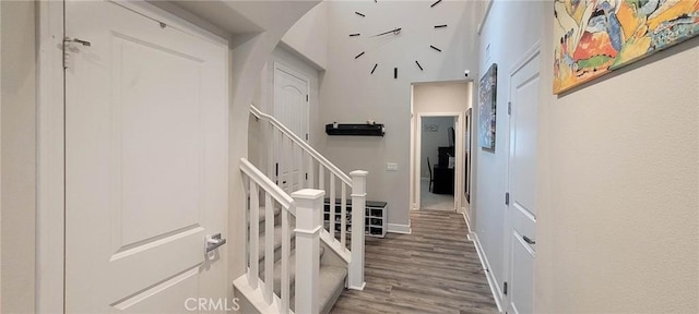 staircase with baseboards, arched walkways, and wood finished floors