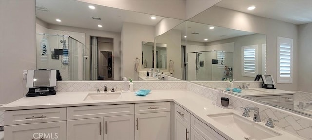 full bathroom featuring double vanity, a sink, and a shower stall