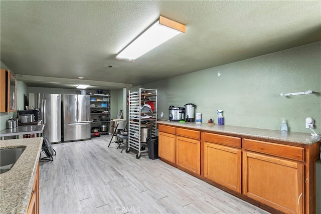 2745 Deer Creek Dr, Running Springs, CA 92382 - kitchen featuring freestanding refrigerator, light wood-type flooring, brown cabinets, a textured ceiling, and stainless steel refrigerator with ice dispenser