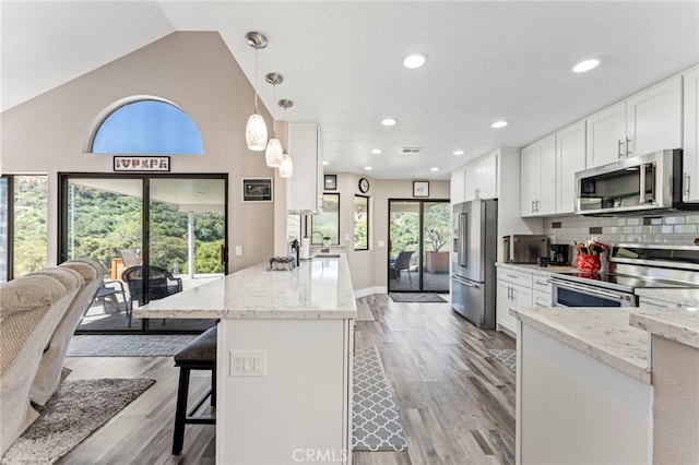 kitchen with light stone countertops, stainless steel appliances, a peninsula, and white cabinetry