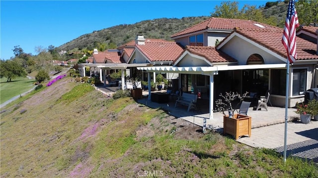 back of house with a pergola, stucco siding, a patio area, a tiled roof, and a mountain view