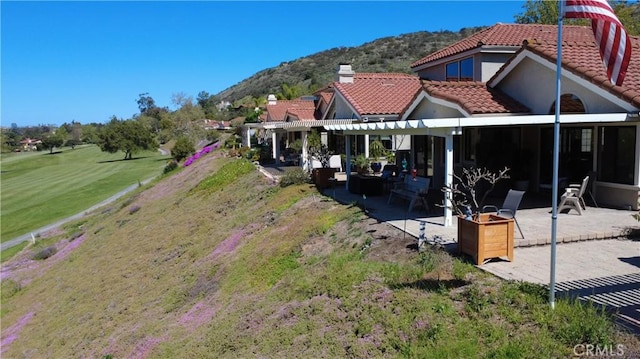 back of property featuring a tiled roof, a patio area, a mountain view, and a pergola