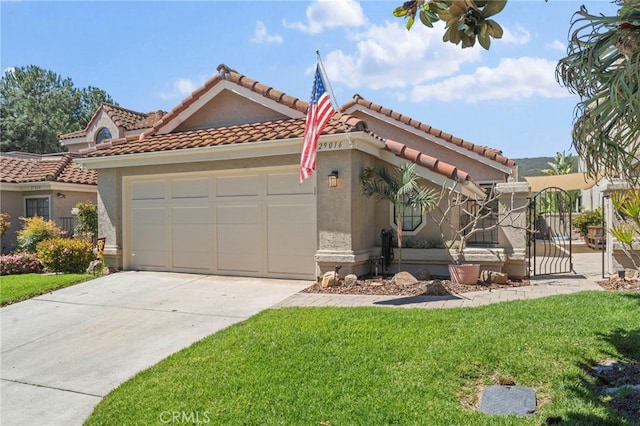 mediterranean / spanish-style home featuring an attached garage, stucco siding, a front yard, a gate, and driveway