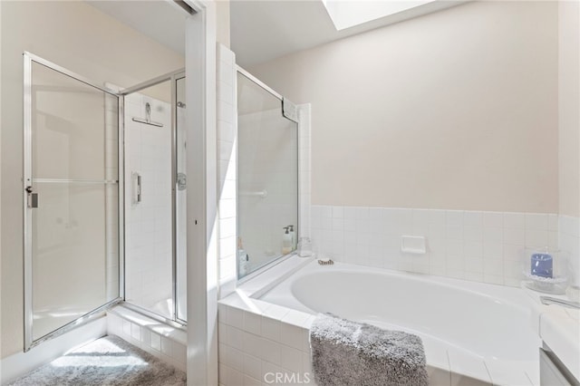 full bathroom featuring a skylight, a garden tub, and a stall shower