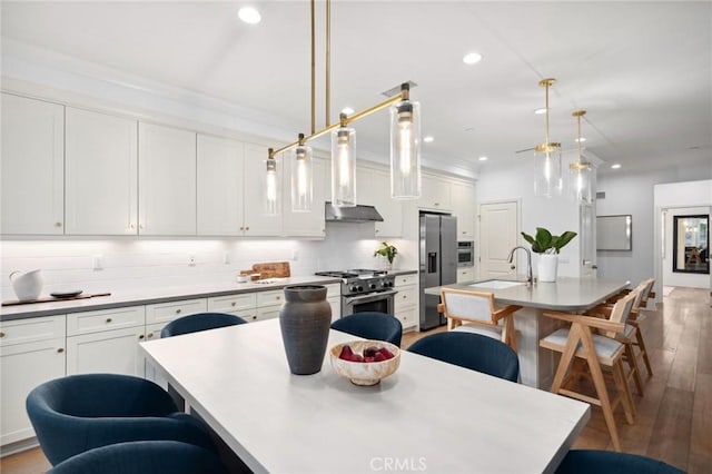 42 Cipresso, Irvine, CA 92618 - kitchen featuring appliances with stainless steel finishes, an island with sink, a kitchen breakfast bar, hardwood / wood-style floors, and recessed lighting