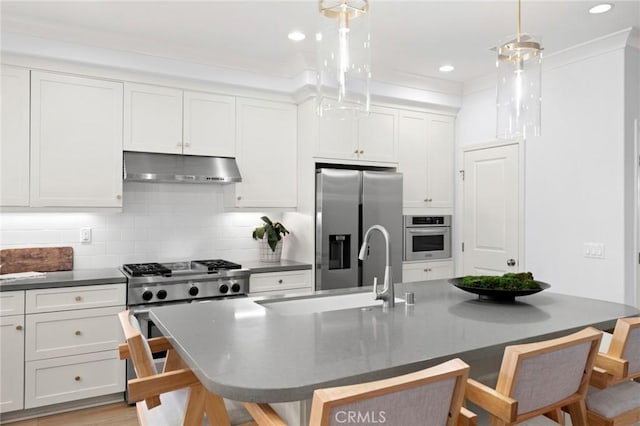 42 Cipresso, Irvine, CA 92618 - kitchen with under cabinet range hood, stainless steel appliances, a breakfast bar, dark countertops, and tasteful backsplash