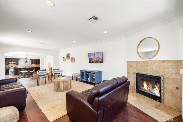 living room with a fireplace, arched walkways, recessed lighting, visible vents, and ornamental molding