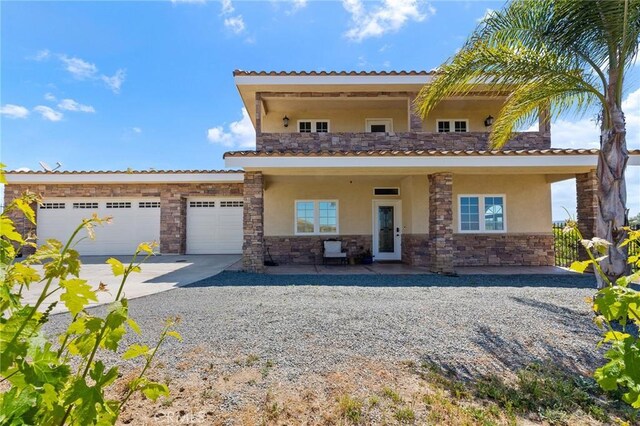 mediterranean / spanish house featuring stucco siding, stone siding, and concrete driveway