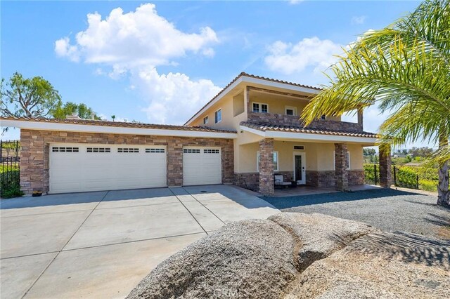 view of front facade featuring stone siding, stucco siding, an attached garage, driveway, and a tile roof