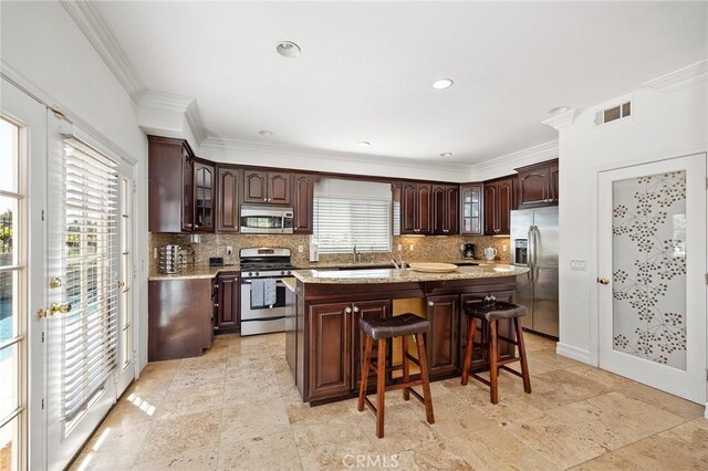kitchen with backsplash, dark brown cabinets, appliances with stainless steel finishes, and glass insert cabinets