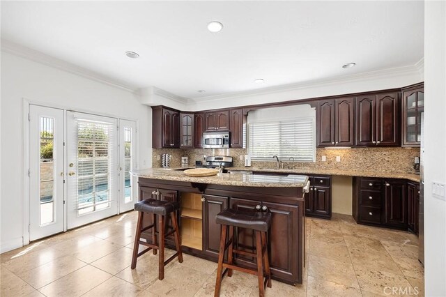 kitchen featuring backsplash, stainless steel appliances, a kitchen breakfast bar, and dark brown cabinets