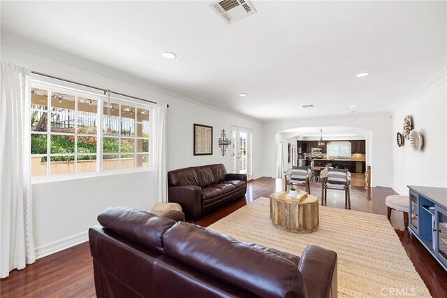 living area featuring a healthy amount of sunlight, arched walkways, dark wood-style floors, and visible vents