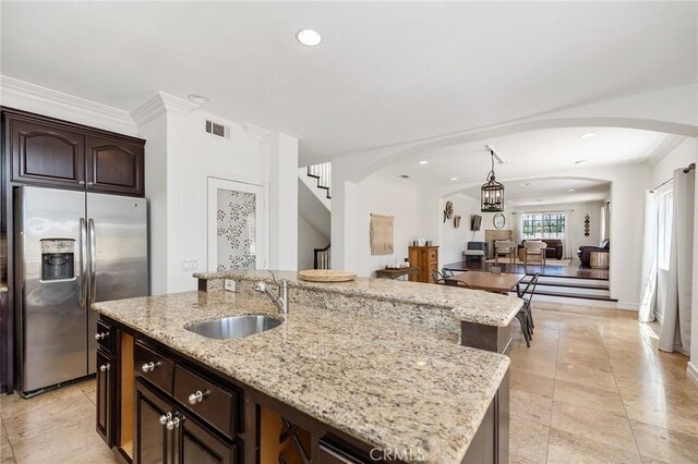kitchen with visible vents, ornamental molding, stainless steel fridge, arched walkways, and a sink