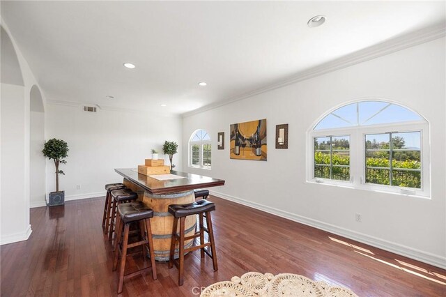 dining room with arched walkways, ornamental molding, dark wood-style floors, and visible vents