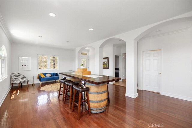 bar featuring ornamental molding, baseboards, recessed lighting, arched walkways, and dark wood finished floors