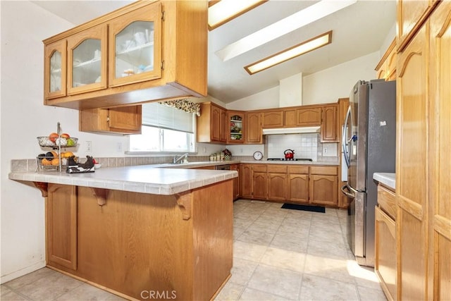 kitchen with appliances with stainless steel finishes, a breakfast bar, a peninsula, under cabinet range hood, and brown cabinetry