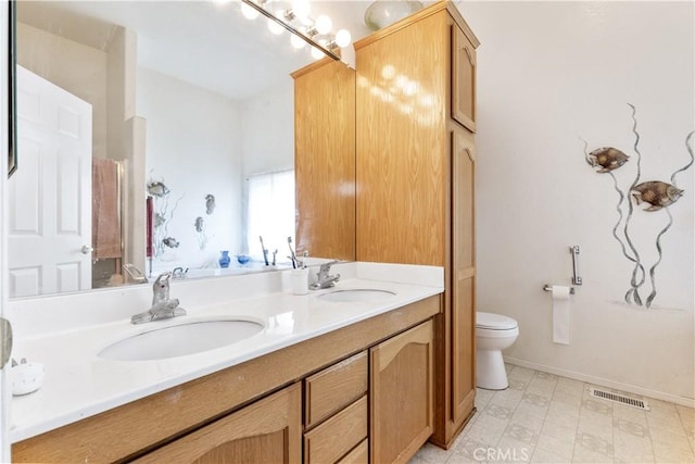 bathroom featuring double vanity, visible vents, a sink, and toilet
