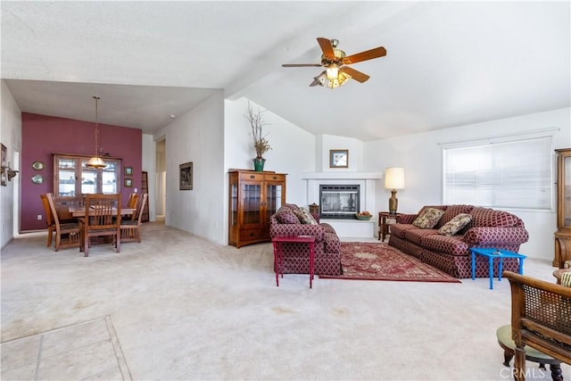 living area featuring ceiling fan, beamed ceiling, high vaulted ceiling, light colored carpet, and a glass covered fireplace
