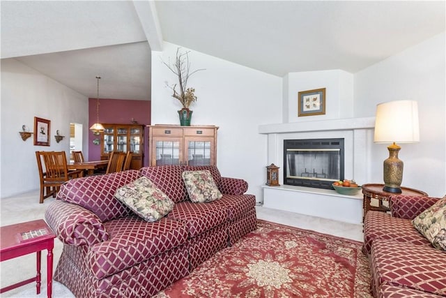 living room featuring a glass covered fireplace, carpet flooring, and lofted ceiling with beams
