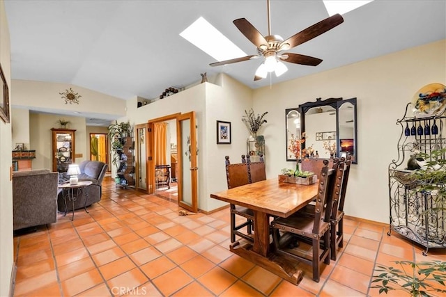 dining room featuring light tile patterned flooring, lofted ceiling with skylight, and ceiling fan