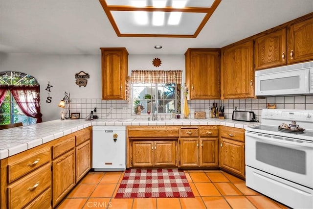 kitchen with a sink, decorative backsplash, white appliances, brown cabinetry, and light tile patterned floors
