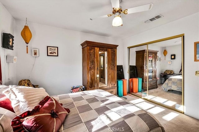 carpeted bedroom with ceiling fan, visible vents, and a closet