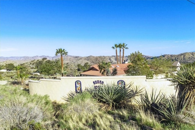 community / neighborhood sign with fence and a mountain view