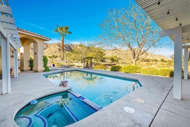 view of pool featuring a mountain view, a patio, and a pool with connected hot tub