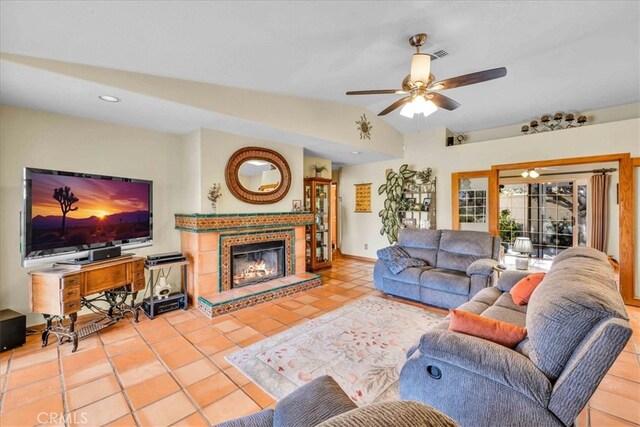 living area featuring tile patterned floors, vaulted ceiling, a glass covered fireplace, recessed lighting, and a ceiling fan