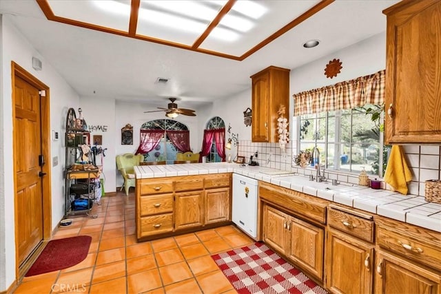 kitchen with brown cabinets, tasteful backsplash, white dishwasher, and a ceiling fan