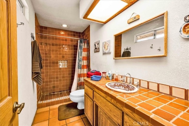 full bath featuring vanity, toilet, tile patterned flooring, and tiled shower