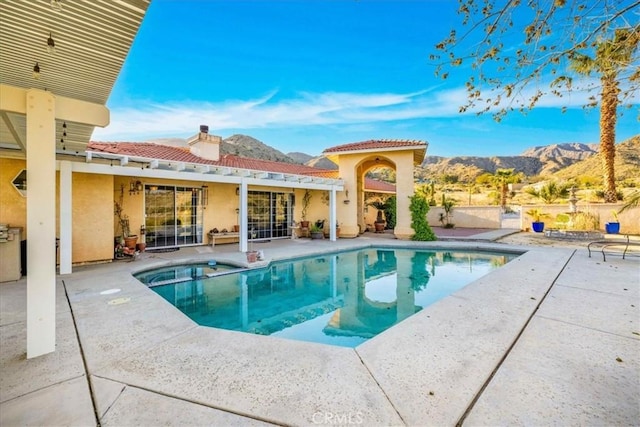 view of pool featuring a pool with connected hot tub, a mountain view, and a patio