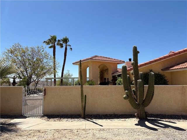 view of front of home featuring fence, a tiled roof, a gate, and stucco siding