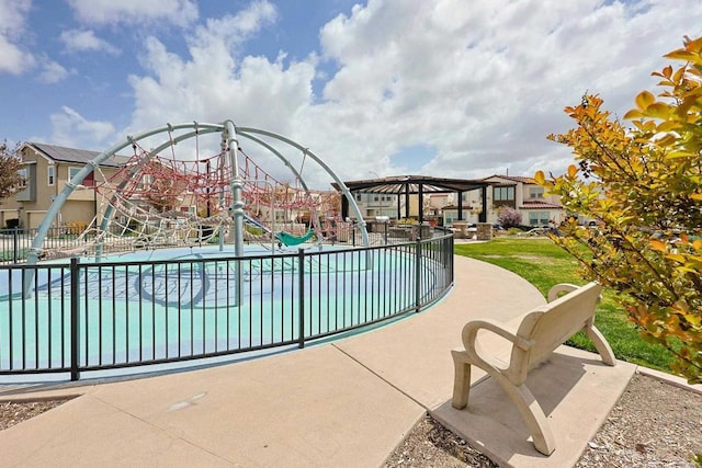 view of pool with fence, a residential view, and playground community