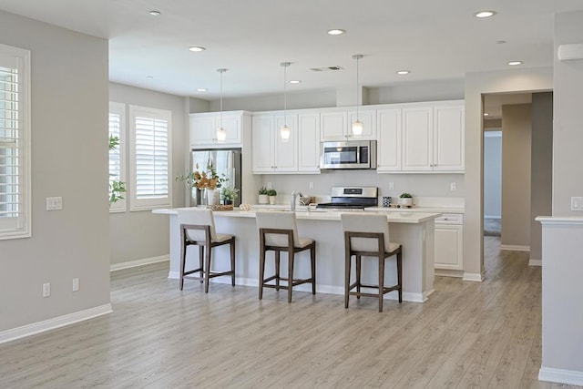 kitchen featuring light wood-style flooring, white cabinets, visible vents, a breakfast bar, and appliances with stainless steel finishes