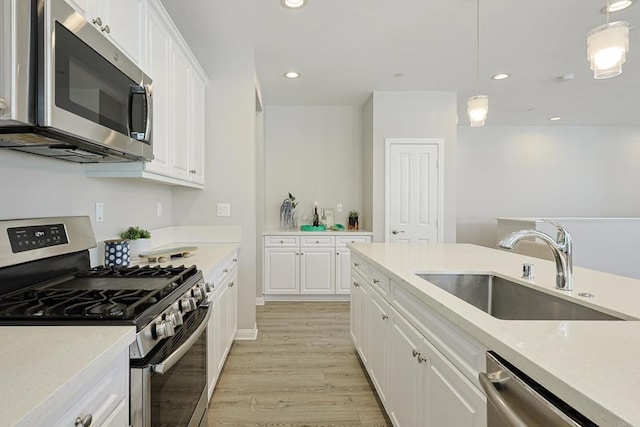 kitchen featuring a sink, light countertops, appliances with stainless steel finishes, white cabinetry, and light wood finished floors