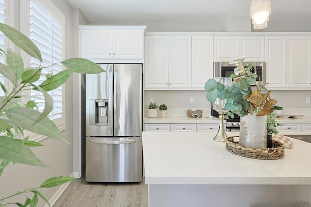 kitchen with stainless steel appliances, light wood finished floors, and white cabinetry