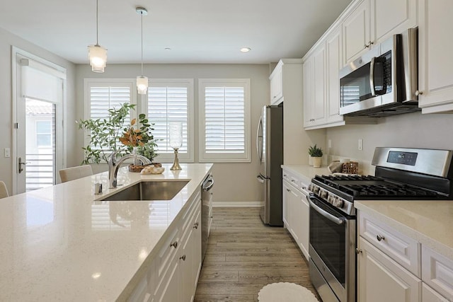 kitchen featuring light wood finished floors, a sink, white cabinetry, and stainless steel appliances