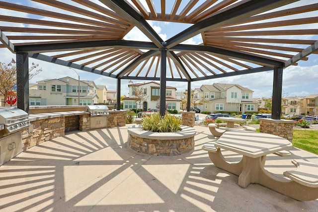 view of patio / terrace featuring a pergola, a residential view, a grill, and an outdoor kitchen