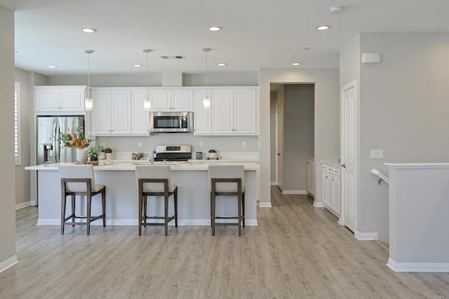 kitchen featuring visible vents, white cabinetry, light wood-style floors, and stainless steel appliances