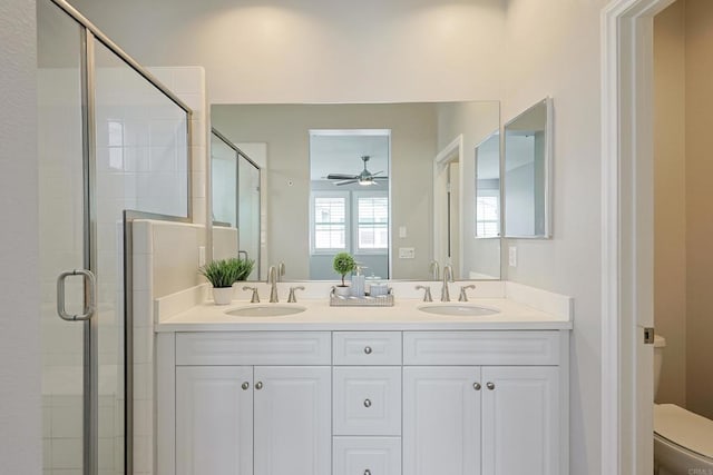 bathroom featuring a sink, ceiling fan, a shower stall, and toilet