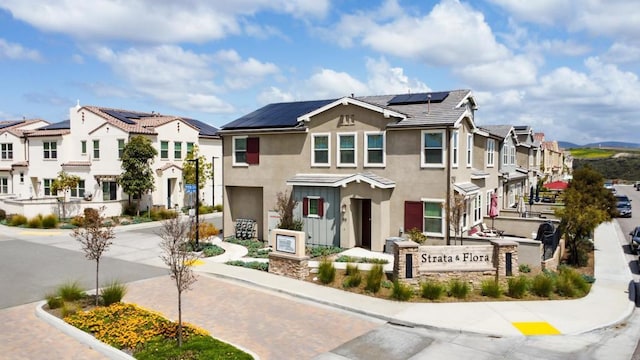 exterior space featuring solar panels, a residential view, a garage, and stucco siding