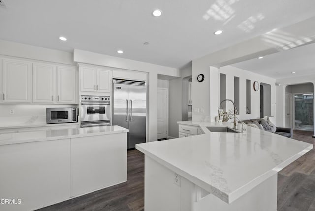 2012 Keltic Lodge Dr, Oxnard, CA 93036 - kitchen with arched walkways, a sink, appliances with stainless steel finishes, a peninsula, and white cabinetry