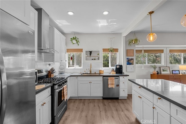 kitchen featuring wall chimney exhaust hood, dark countertops, a sink, and stainless steel appliances