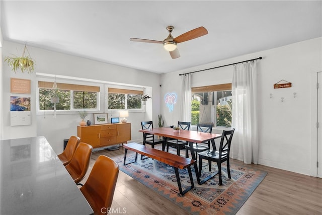 dining space with baseboards, a ceiling fan, and wood finished floors