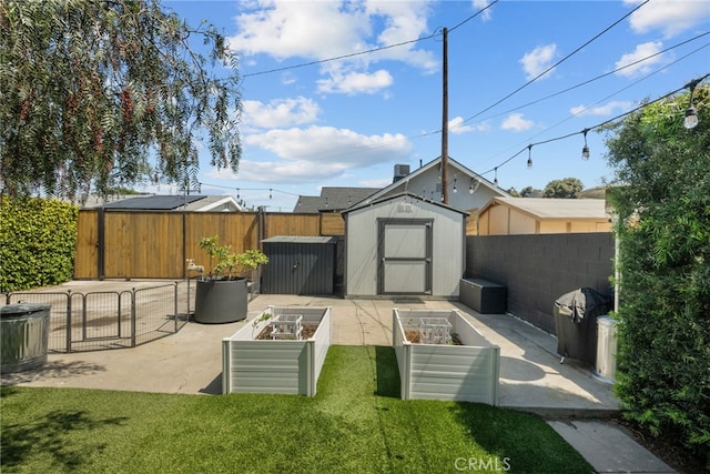 view of yard with a shed, a patio area, a vegetable garden, a fenced backyard, and an outbuilding