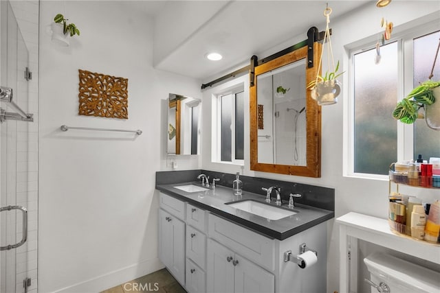 full bath with a stall shower, double vanity, a sink, and baseboards